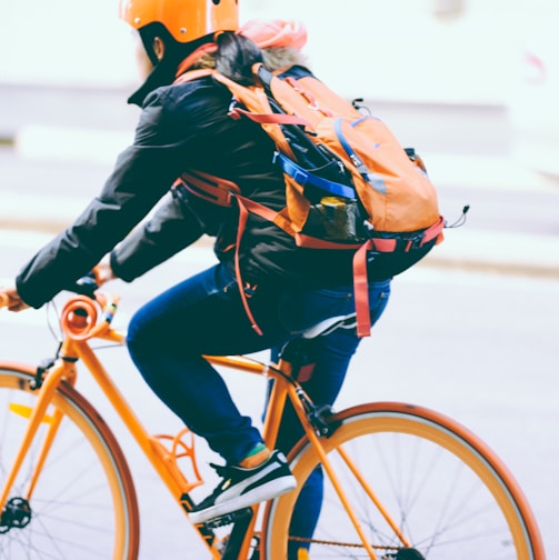 closeup photo of person riding a orange bicycle