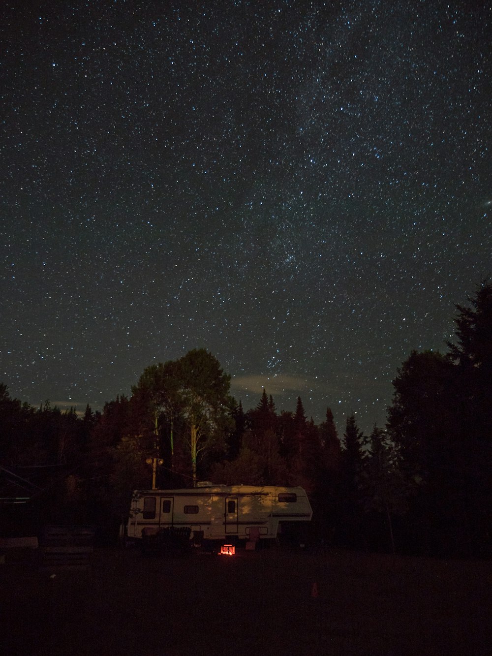 夜間の木々に囲まれた白いRVトレーラー