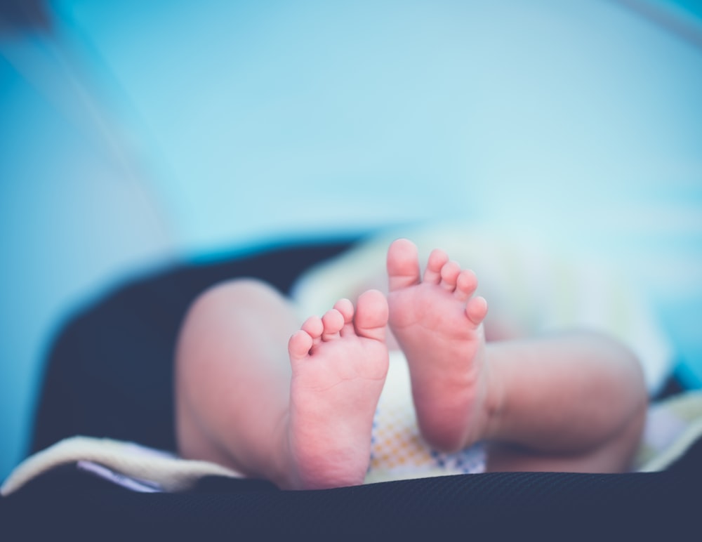 shallow focus photography of baby wearing white diaper lying