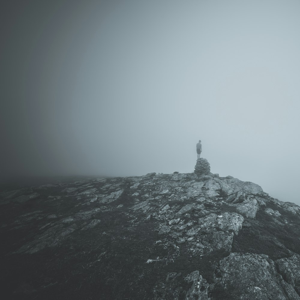 Person, die auf einem Felsen auf dem Gipfel eines Hügels steht