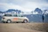 Smiling young man standing beside a camper van with a scenic mountain background