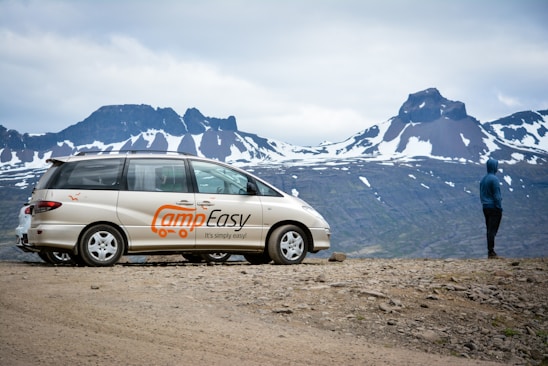 A scenic view of a camper parked in nature with mountains in the background.