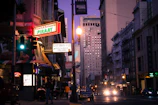 Street view of a vibrant East Orange neighborhood with restaurant signs glowing at dusk.