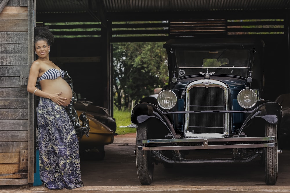 Mujer embarazada cerca de coche clásico