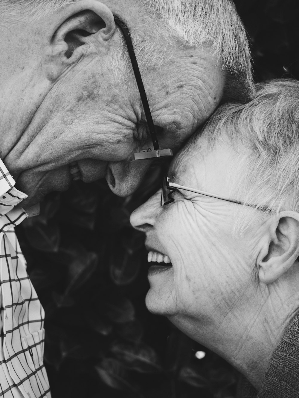 Elderly man and woman touch foreheads in black and white photo