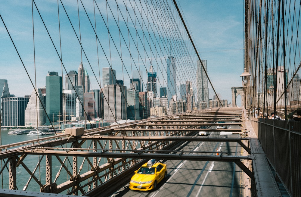 yellow sedan passing on bridge