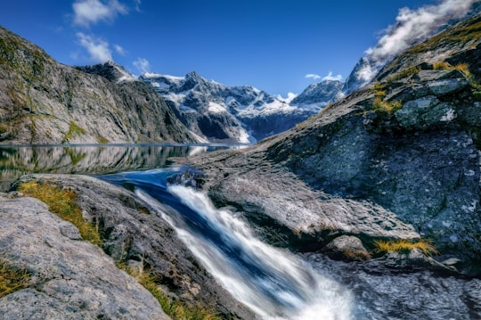 waterfalls surrounded mountain under blue and white skies in Fiordland National Park New Zealand