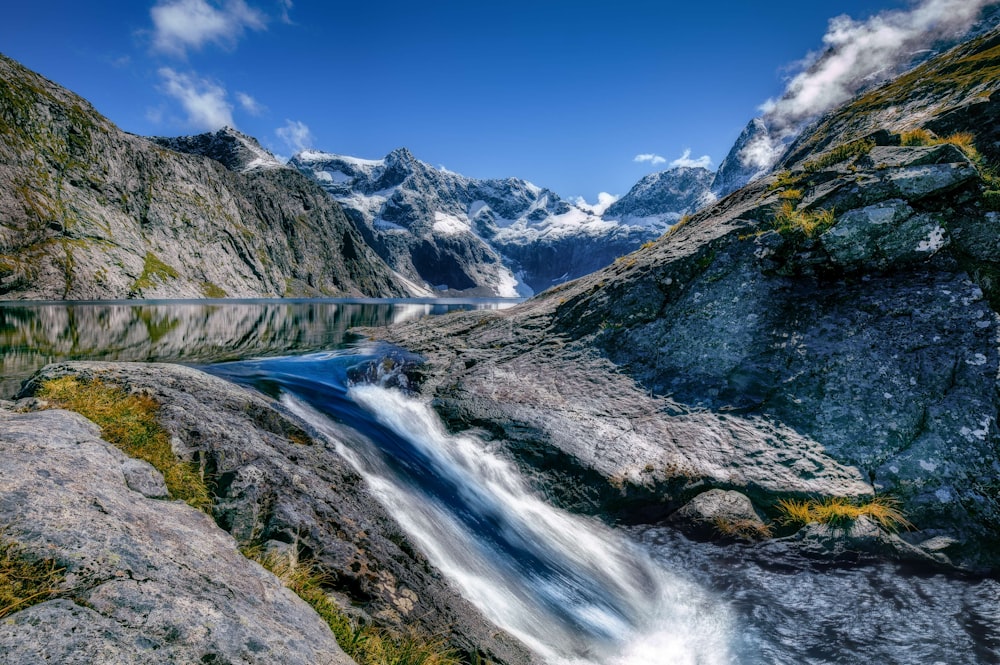 waterfalls surrounded mountain under blue and white skies