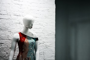 A casual photo of a mannequin wearing a graphic tee standing in front of a textured brick wall