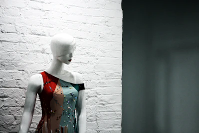 A flowing summer dress in soft pastel tones displayed on a mannequin against a bright, airy background.