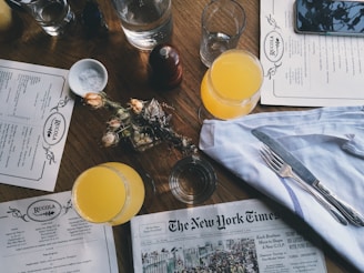 grey New York Time newspaper on table together with juice glasses