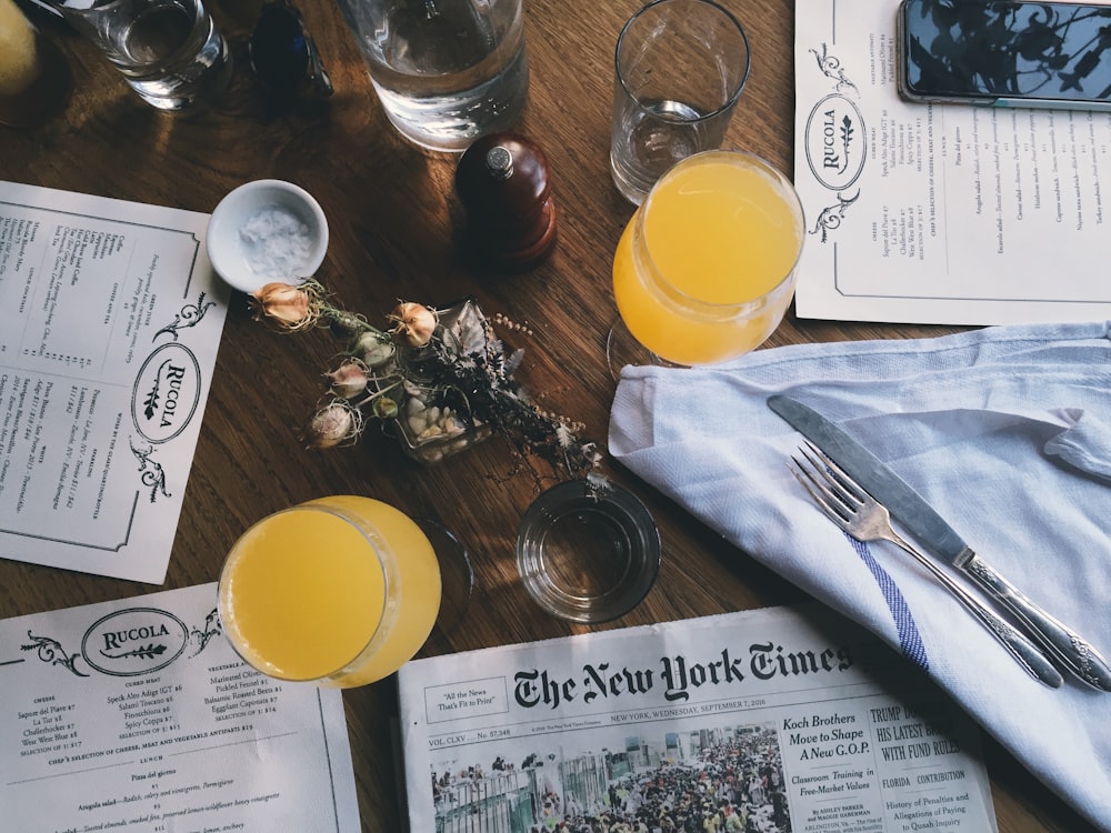 grey New York Time newspaper on table together with juice glasses