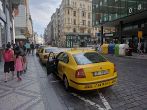 A fleet of yellow taxis lined up on a cobblestone street with traditional Portuguese buildings in the background.