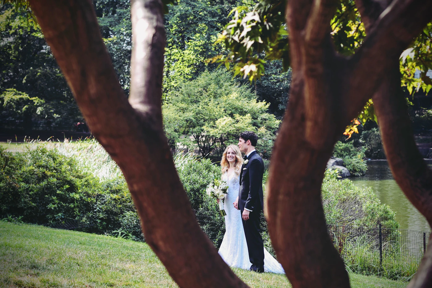 Bride and groom in elegant formal wedding attire standing together in a manicured park garden setting