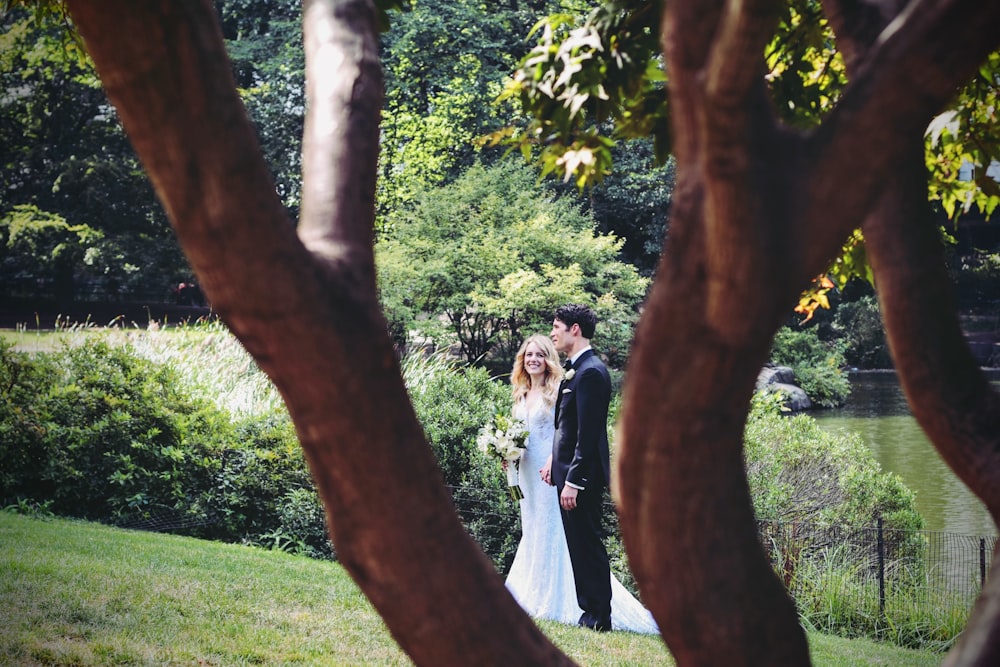 man and woman standing on grass field near tree