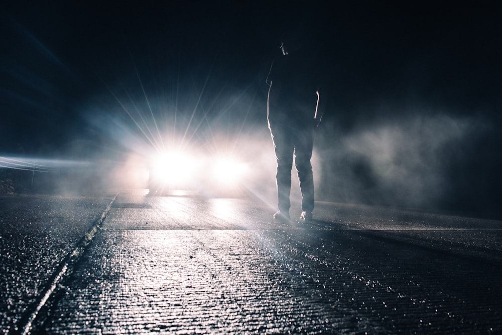 hombre de pie frente a un coche iluminado