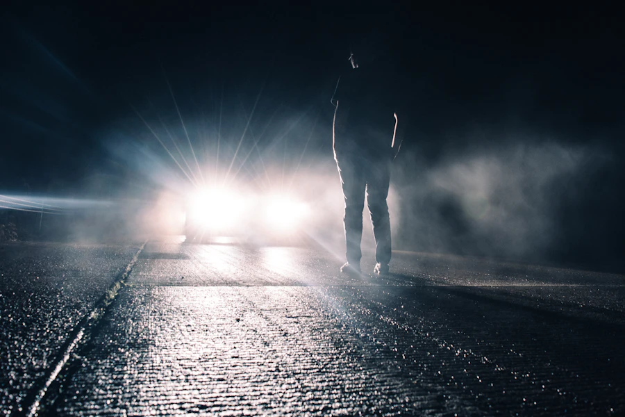 Silhouet van een persoon voor de koplampen van een auto in de nacht