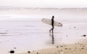 man holding surf board while standing on shore at daytime