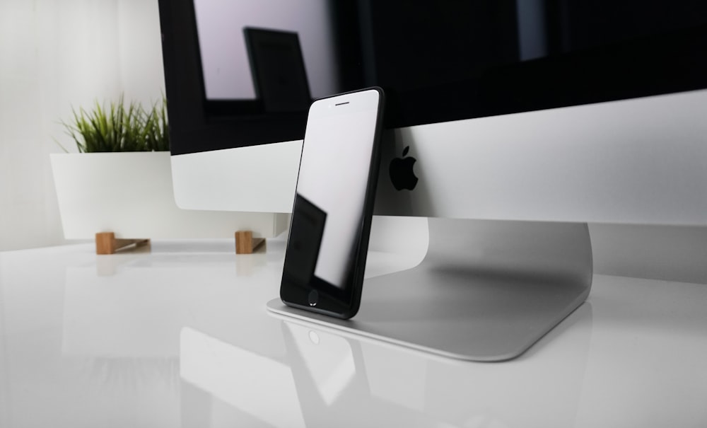 black iPhone 7 leaning on silver iMac