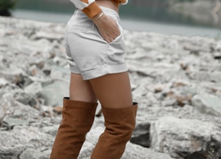 woman in white short shorts looking on rocks while putting her hand in pocket