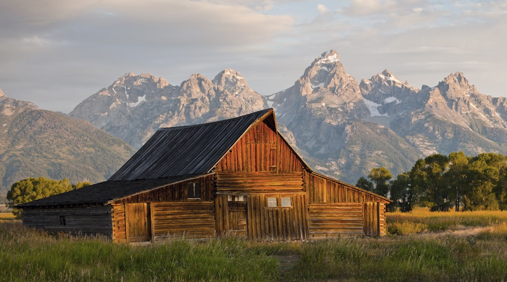 brown wooden house near brown mountain and green trees during daytime