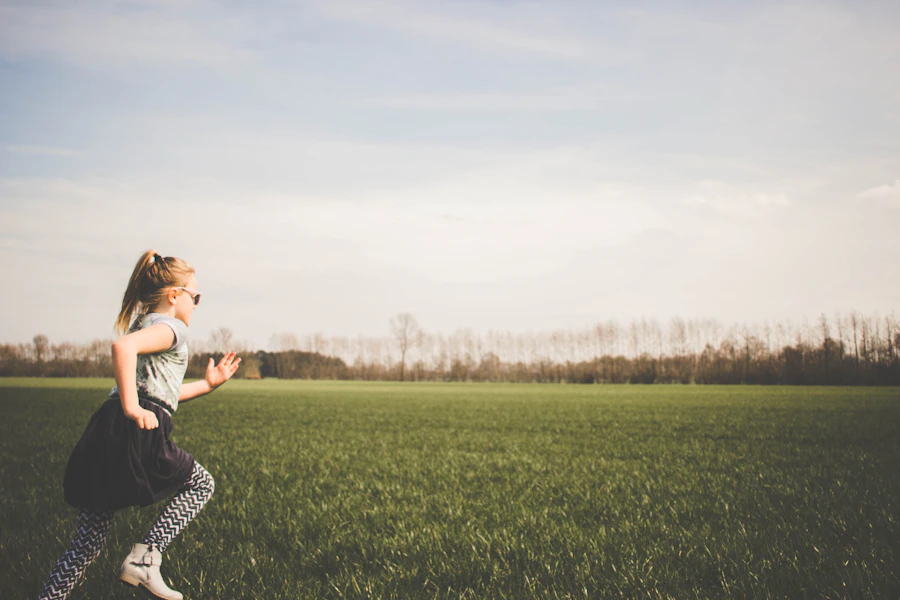 A child runs across an open green field, captured mid-stride in profile, full of motion