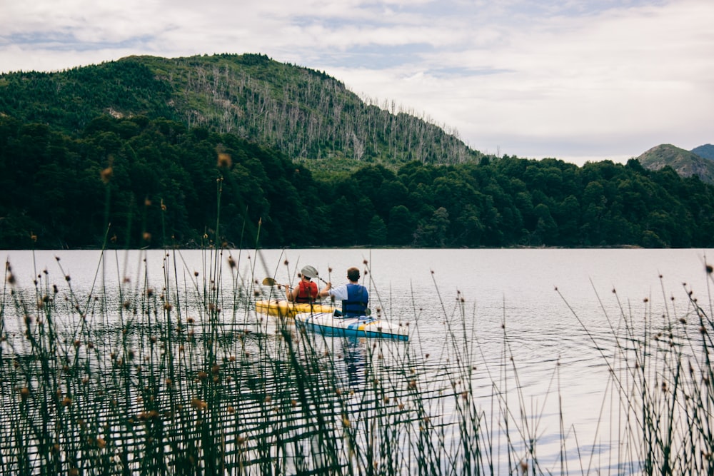 two person kayaking near mountain