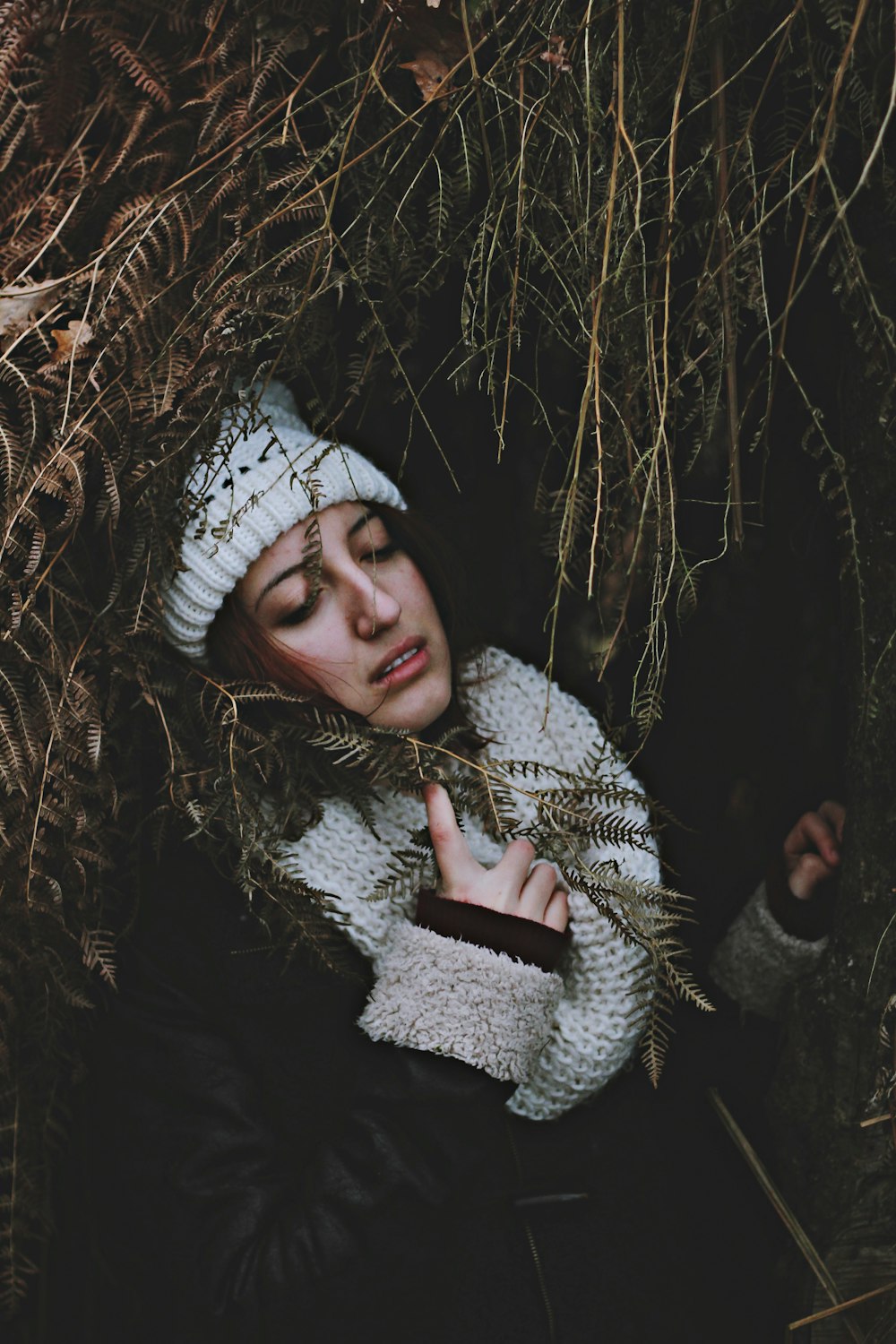 woman under arc of dried leaves holding scarf