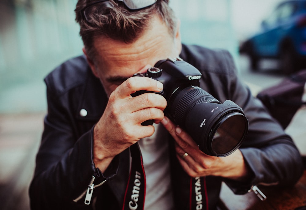 man holding up Canon DSLR camera