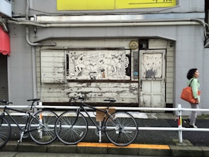 A stylish messenger bag hanging on a bike handlebar against a vibrant city street mural.
