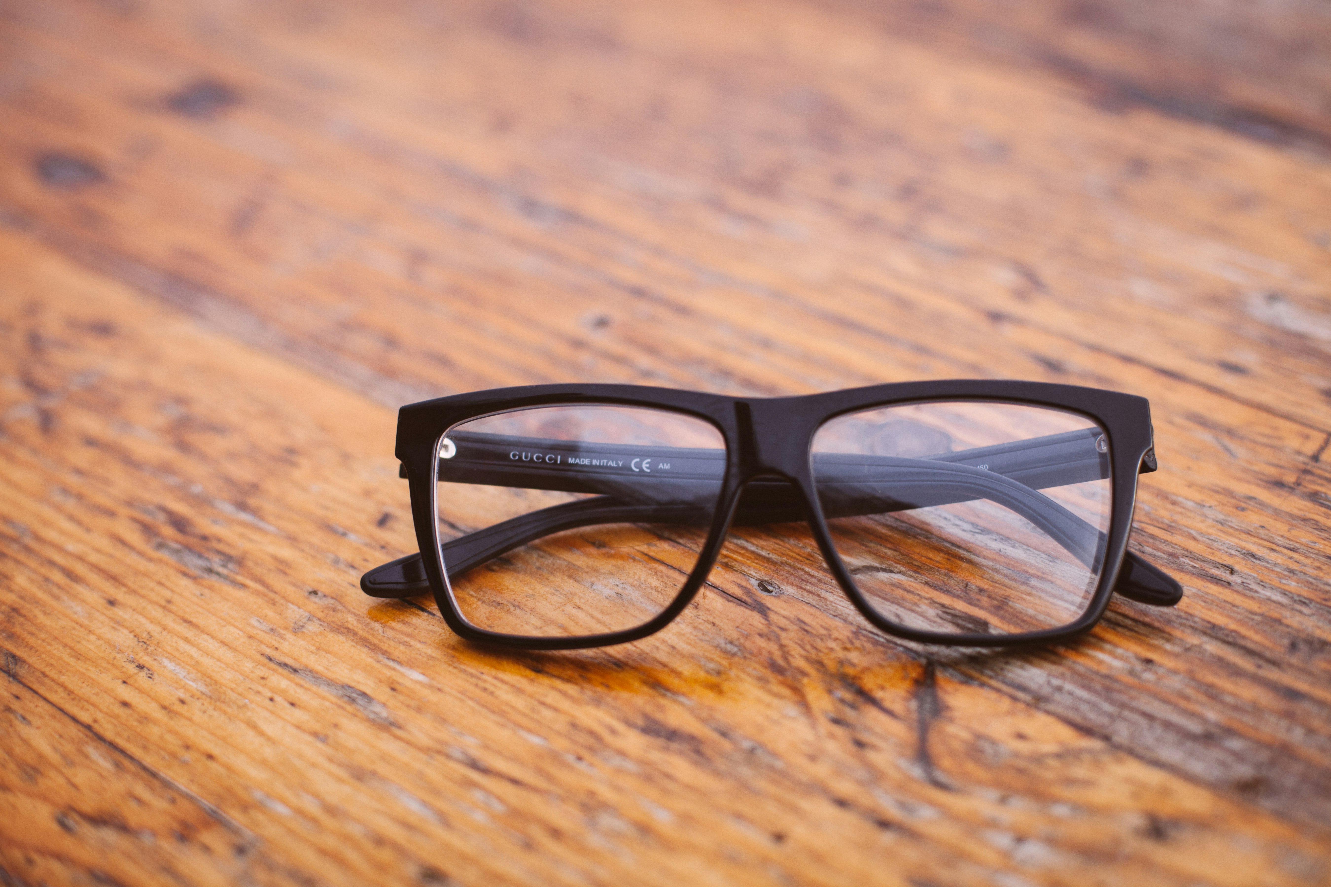 black framed Wayfarer-style eyeglasses on wooden surface