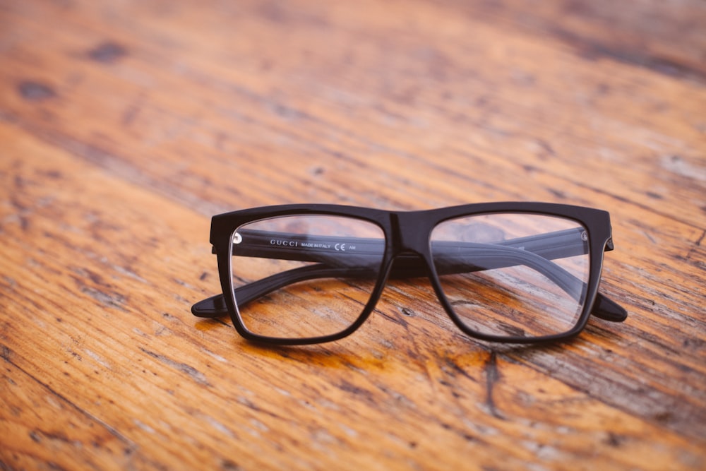 black framed Wayfarer-style eyeglasses on wooden surface
