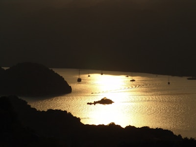 Sunset casting warm golden light over the Baía dos Golfinhos with the boat anchored nearby.