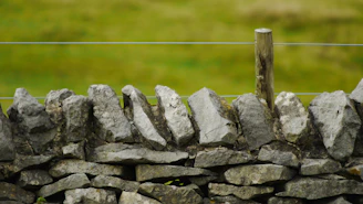 A sturdy stone fence blending naturally with a countryside landscape at dusk.