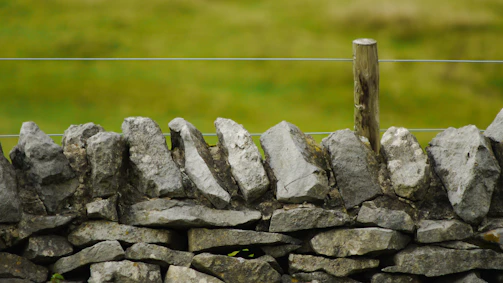 A sturdy stone fence blending naturally with a countryside landscape at dusk.