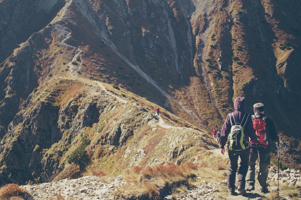 two people walking on top of moutnain