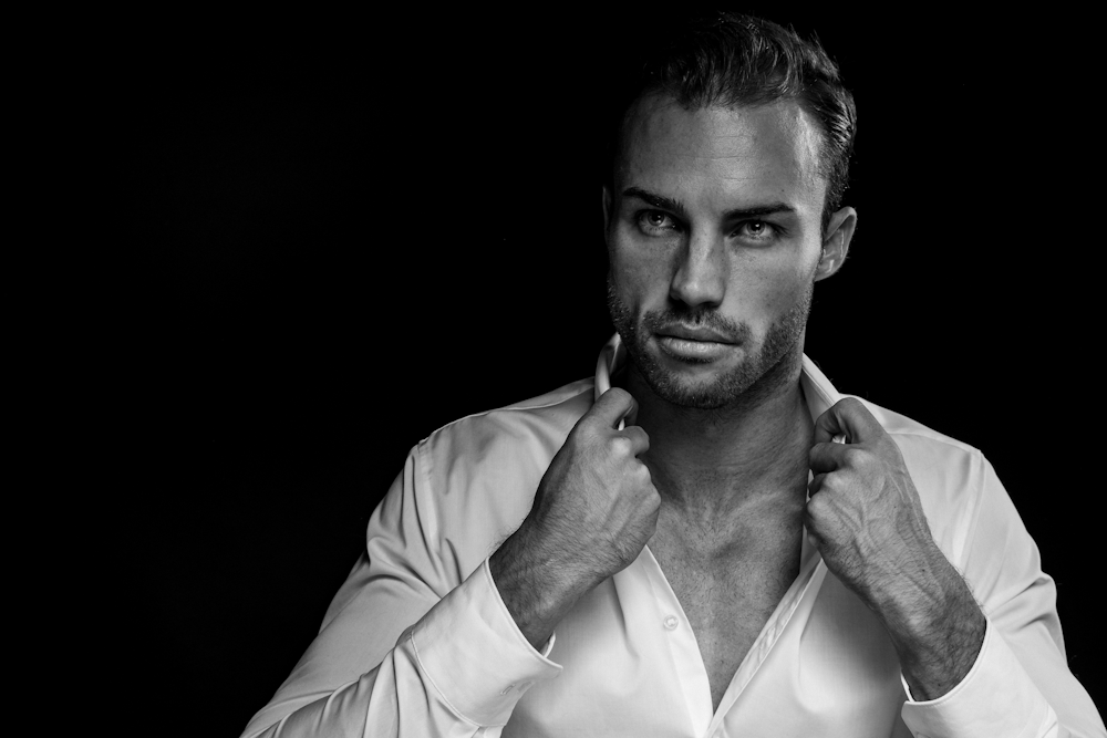 grayscale portrait of man wearing white dress shirt on black background