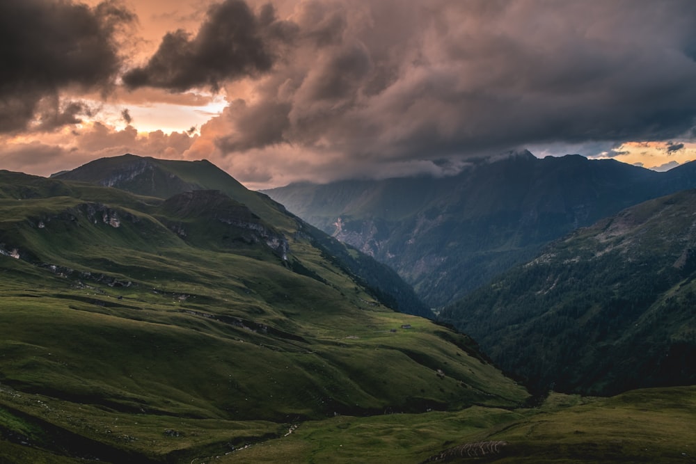 montagne couverte d’herbe verte sous des nuages gris