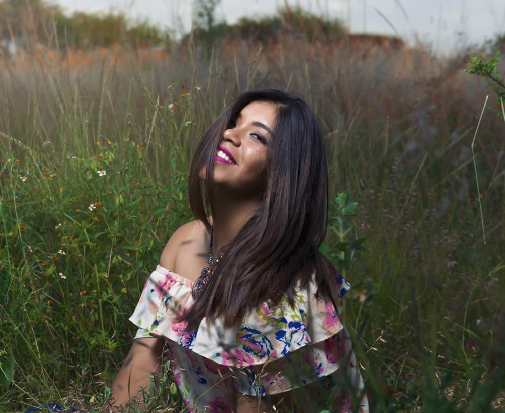 woman in yellow and white floral dress sitting on green grass field during daytime