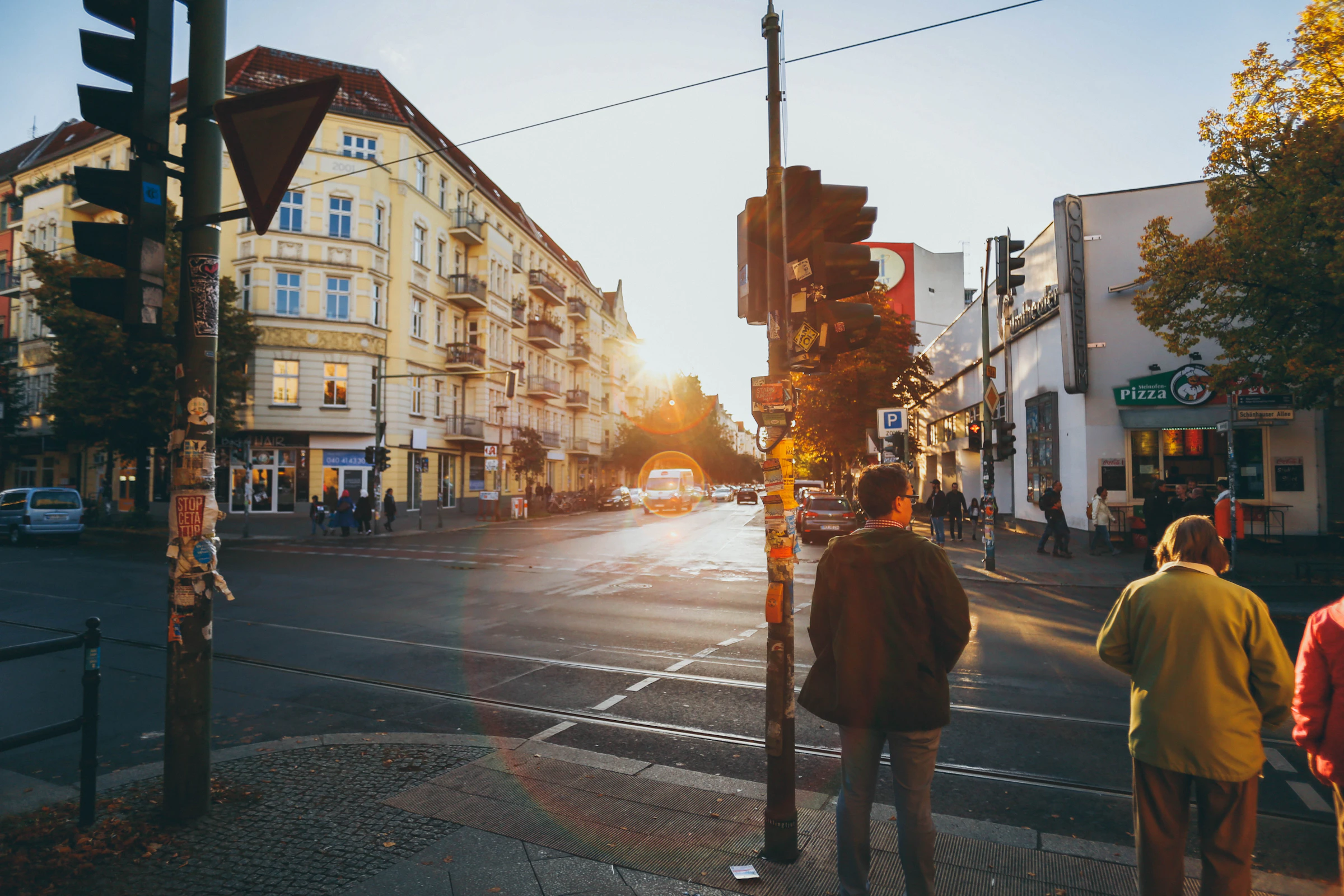 Berliner Straßenkreuzung im Abendlicht mit Passanten vor Altbaufassaden