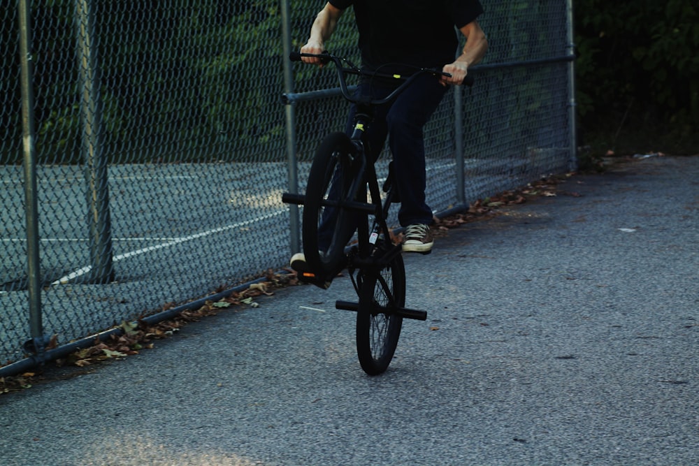 person riding BMX bike near chain link fence