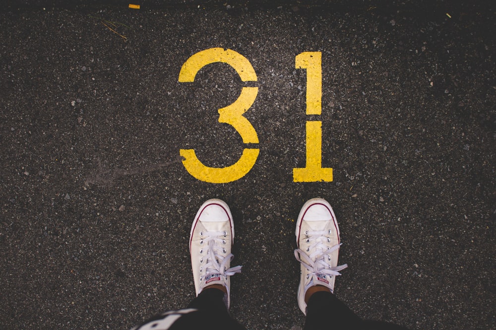 person standing beside 31 painted gray concrete road at daytime