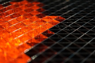 Close-up of a glowing graphene lattice structure with orange highlights on a black background.