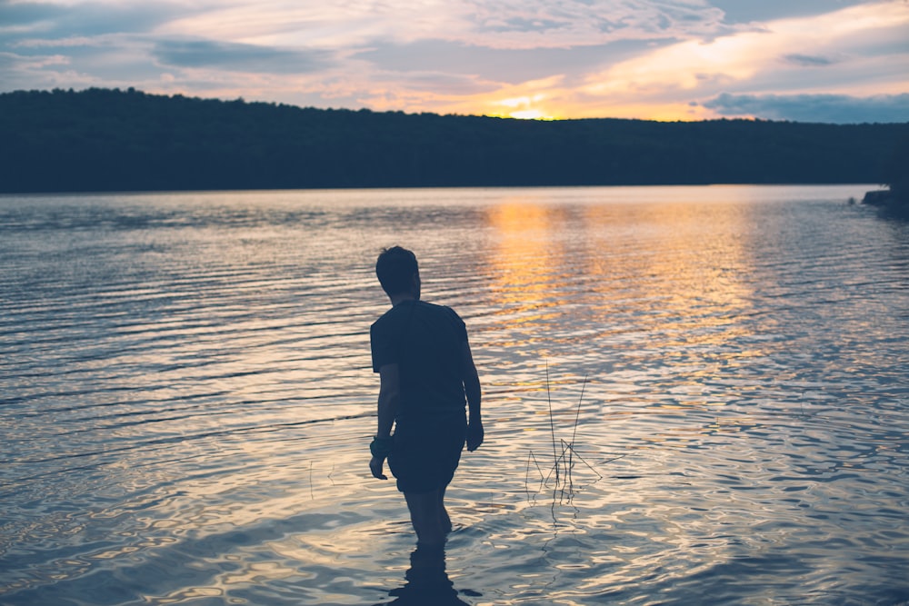 a man standing in the water at sunset