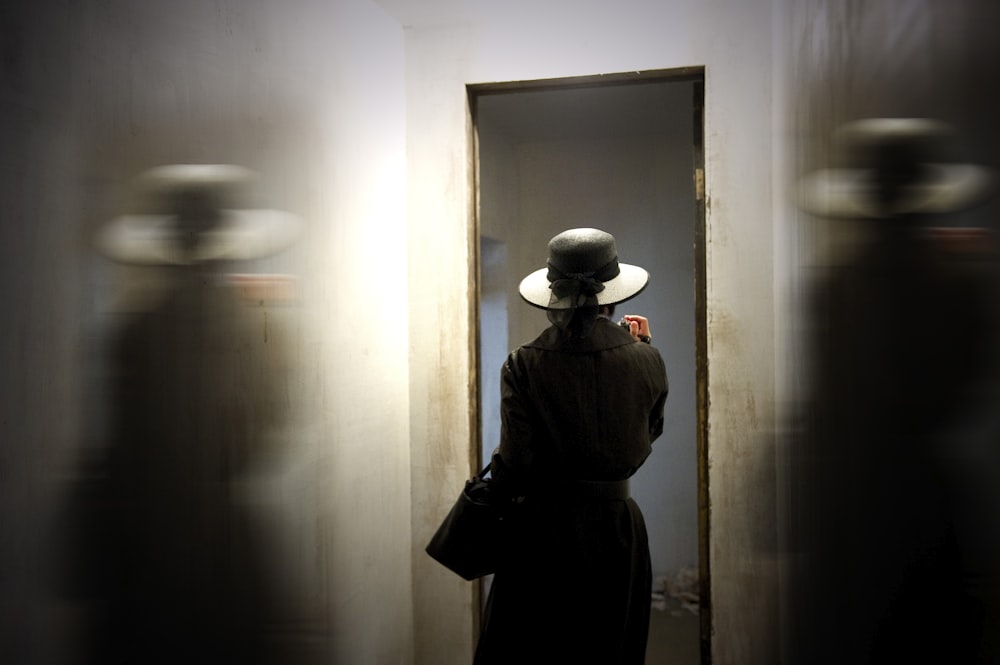 person wearing hat carrying bag while standing in front of door