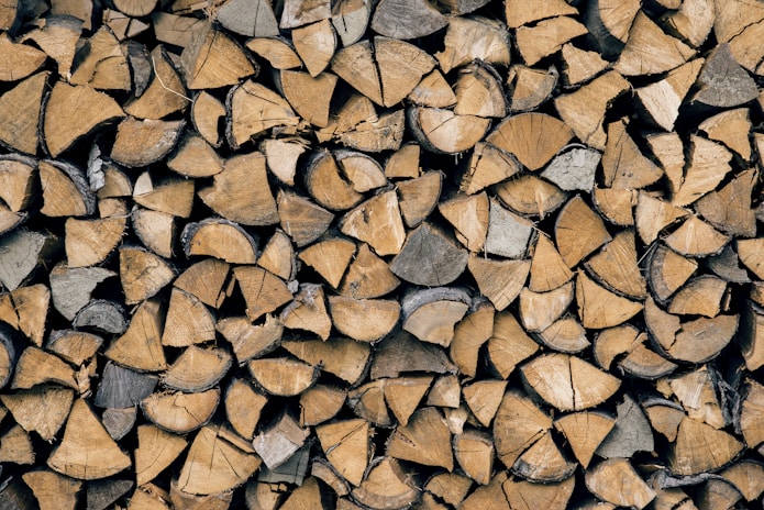 A stack of neatly arranged chopped firewood, featuring pieces of varying sizes and shapes, with visible textures and tree rings.