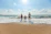 man, woman and child holding hands on seashore