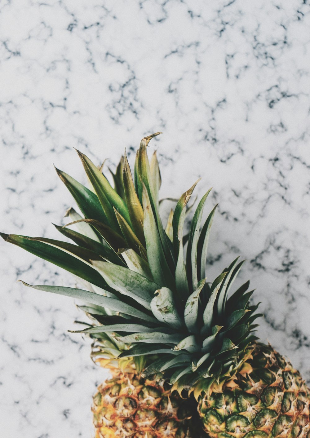 two pineapple fruits on white surface