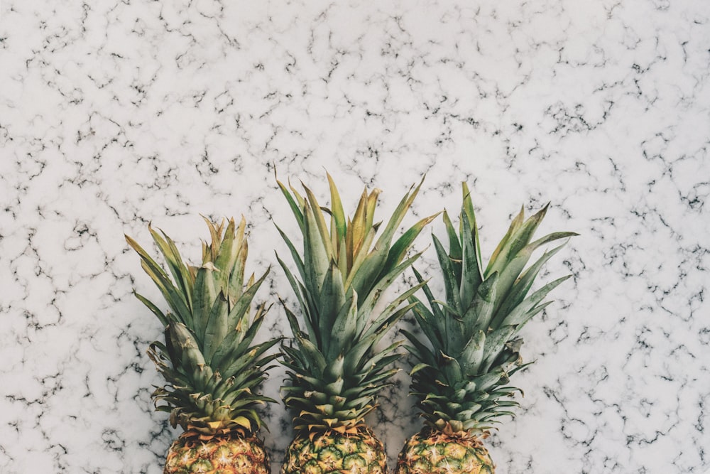 three yellow pineapple fruits on white surface