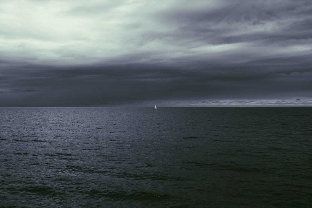 white boat on sea under gray clouds